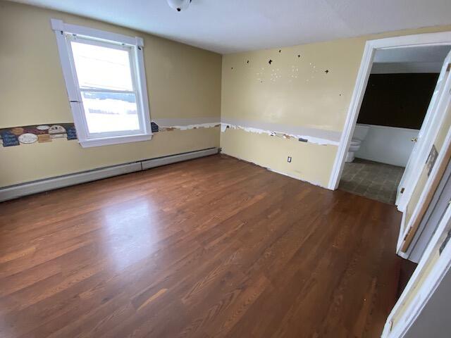 empty room featuring dark hardwood / wood-style floors and baseboard heating