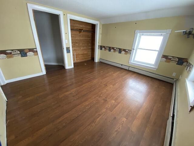 spare room with a baseboard heating unit and dark wood-type flooring