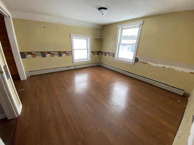 empty room featuring a baseboard radiator and dark hardwood / wood-style flooring