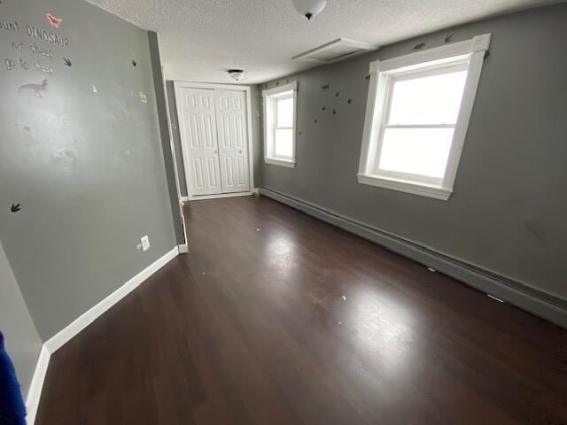 unfurnished bedroom featuring dark hardwood / wood-style flooring, a closet, and a textured ceiling