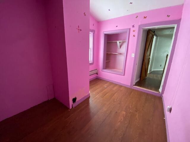 unfurnished room featuring a baseboard heating unit and dark hardwood / wood-style flooring