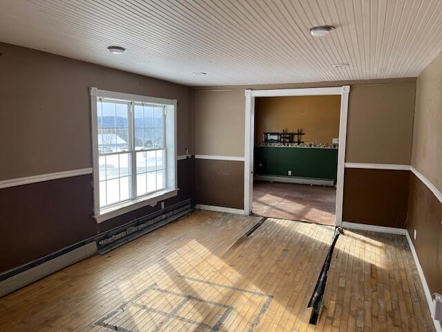 unfurnished room with hardwood / wood-style flooring, a baseboard radiator, and wood ceiling