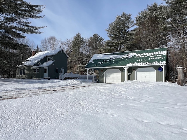 snow covered property with a garage and an outdoor structure