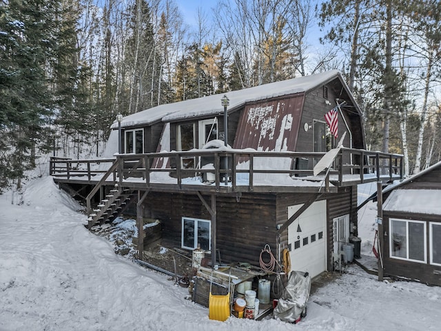 snow covered property with a garage and a wooden deck