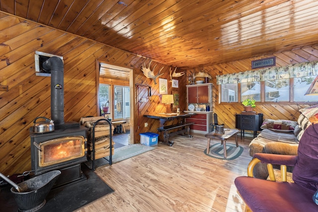 living room with wood ceiling, light hardwood / wood-style floors, and a wood stove