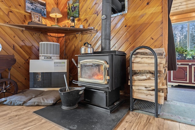 interior details featuring wood-type flooring, wooden walls, and a wood stove