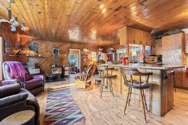 living room featuring a wood stove, wooden ceiling, and light hardwood / wood-style flooring