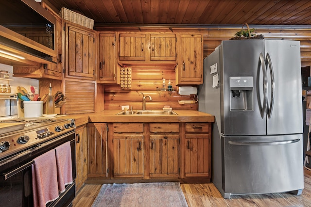 kitchen featuring rustic walls, sink, wooden ceiling, appliances with stainless steel finishes, and light hardwood / wood-style floors