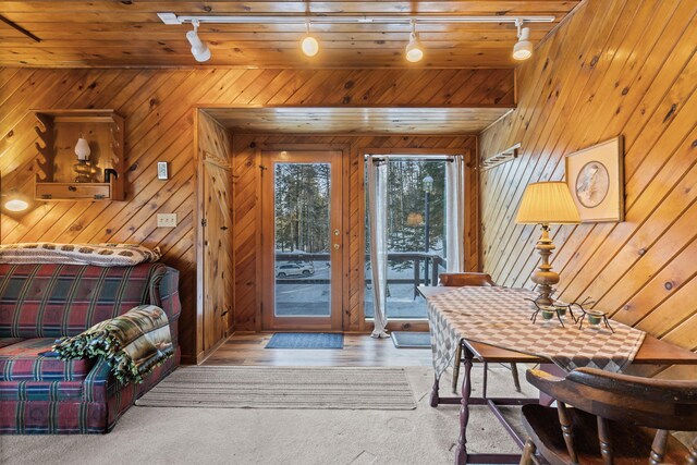 interior space featuring rail lighting, light wood-type flooring, wood ceiling, and wooden walls