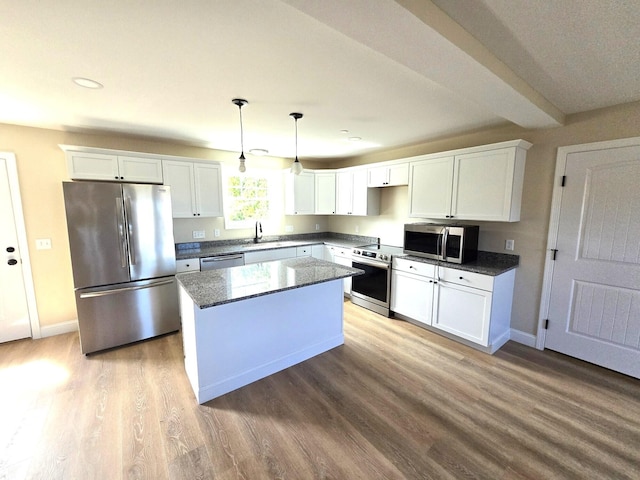 kitchen with pendant lighting, sink, white cabinetry, stainless steel appliances, and a kitchen island