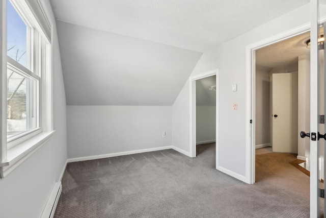 additional living space featuring a textured ceiling, a wealth of natural light, vaulted ceiling, and carpet flooring