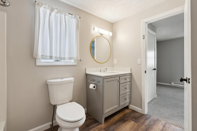 bathroom featuring toilet, wood-type flooring, a textured ceiling, baseboard heating, and vanity