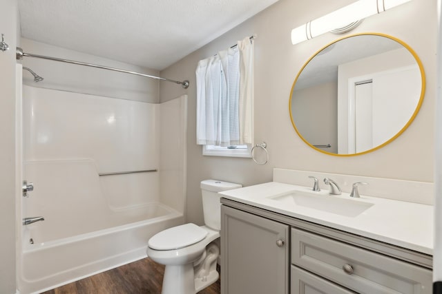 full bathroom with washtub / shower combination, hardwood / wood-style floors, vanity, a textured ceiling, and toilet