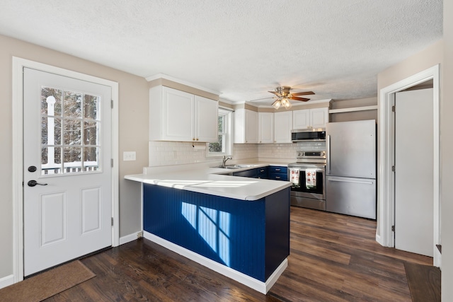 kitchen with sink, white cabinetry, stainless steel appliances, dark hardwood / wood-style flooring, and kitchen peninsula