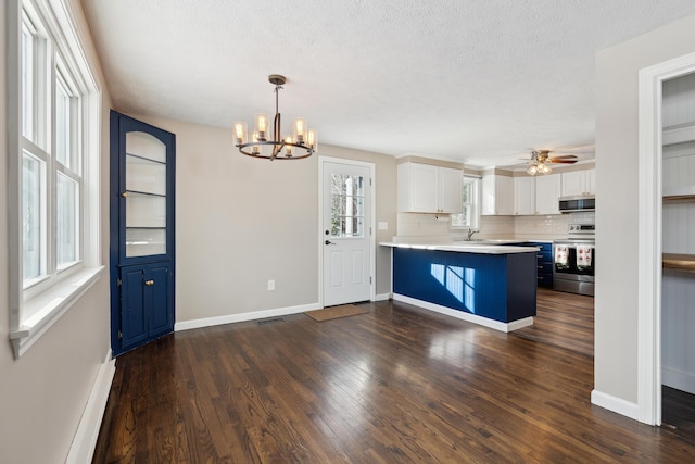 kitchen featuring appliances with stainless steel finishes, hanging light fixtures, a kitchen breakfast bar, dark hardwood / wood-style floors, and white cabinets