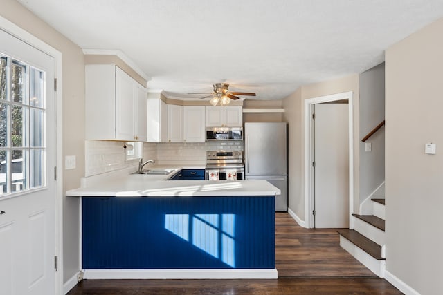 kitchen featuring appliances with stainless steel finishes, kitchen peninsula, sink, and white cabinets