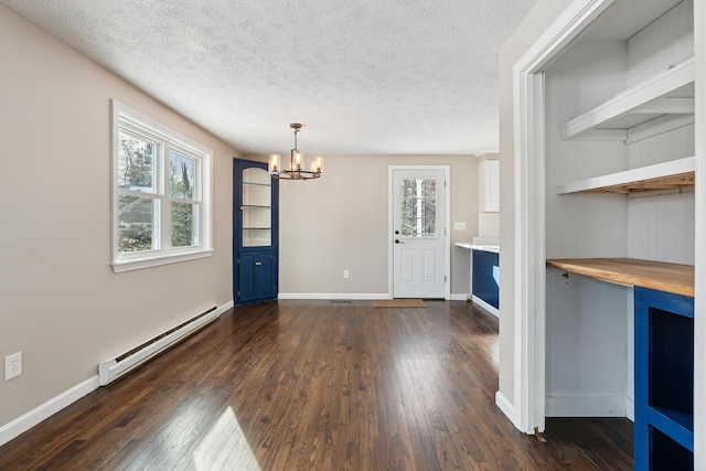 unfurnished dining area with plenty of natural light, a baseboard heating unit, dark wood-type flooring, and a textured ceiling