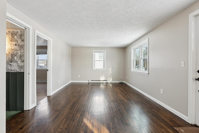 spare room featuring baseboard heating, dark hardwood / wood-style flooring, and a textured ceiling