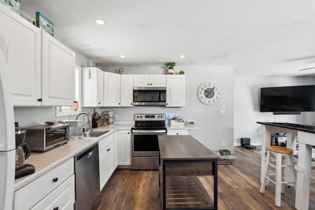 kitchen featuring stainless steel appliances, dark hardwood / wood-style flooring, sink, and white cabinets