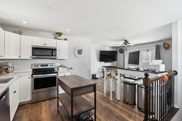 kitchen featuring white cabinetry, ceiling fan, appliances with stainless steel finishes, and dark wood-type flooring