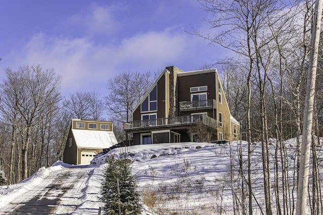 snow covered house featuring a balcony and a deck