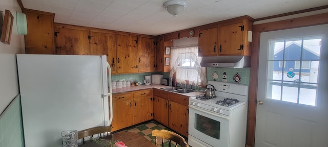 kitchen featuring white appliances, sink, and backsplash