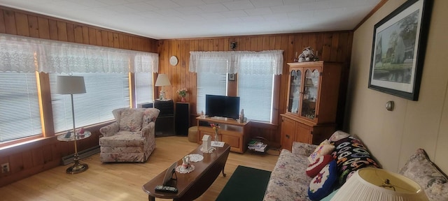 living room featuring wooden walls, light hardwood / wood-style floors, and a baseboard heating unit