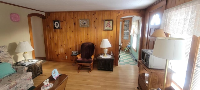 sitting room with crown molding, light hardwood / wood-style flooring, and wooden walls