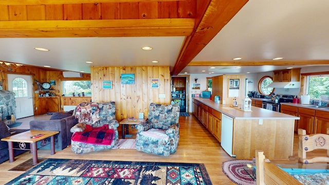 kitchen with wood walls, sink, light hardwood / wood-style floors, beam ceiling, and stainless steel electric range