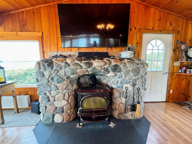 interior details with a wood stove, hardwood / wood-style floors, wood ceiling, and wood walls