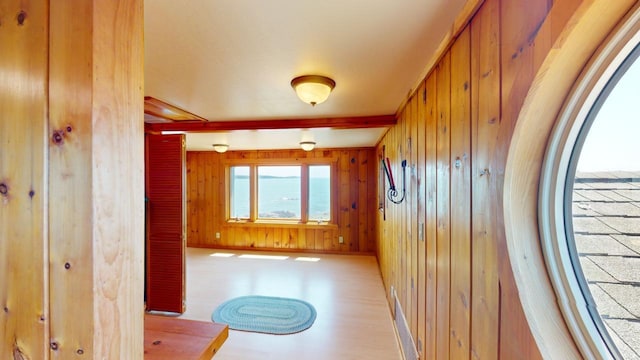 hallway with beamed ceiling, a water view, hardwood / wood-style floors, and wooden walls