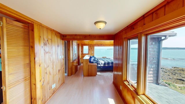 hallway featuring a water view, wooden walls, and light hardwood / wood-style floors