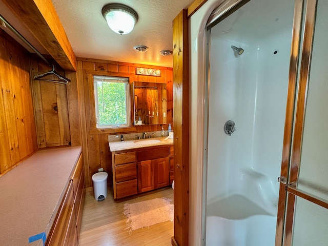 bathroom with walk in shower, vanity, hardwood / wood-style flooring, and wood walls