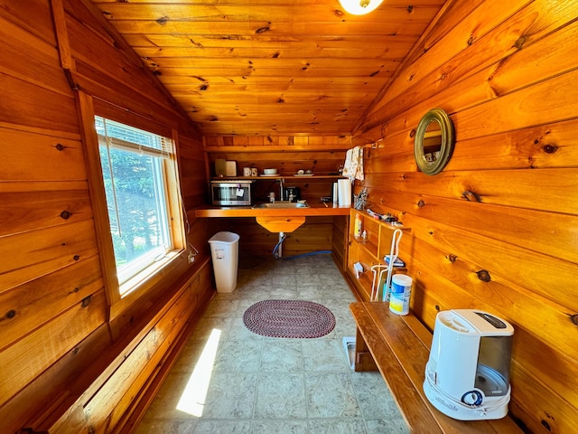 interior space featuring vaulted ceiling, wood ceiling, wooden walls, and kitchen peninsula