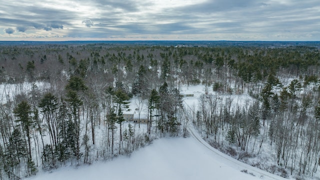 snowy aerial view featuring a wooded view