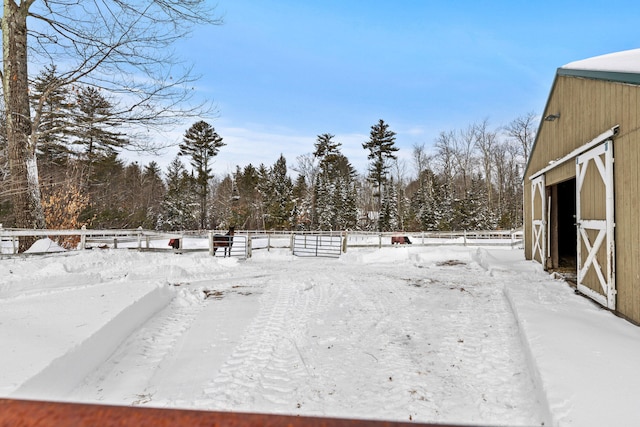 yard layered in snow featuring an outbuilding and fence