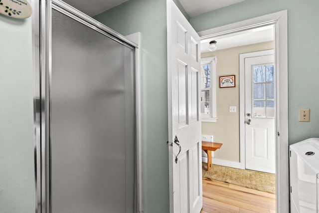 full bathroom with a stall shower, wood finished floors, and baseboards