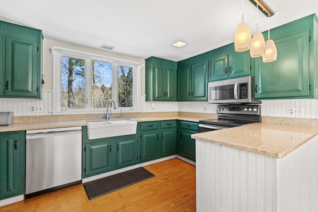 kitchen featuring appliances with stainless steel finishes, a sink, visible vents, and light wood-style floors