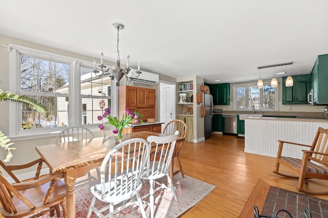 dining space featuring light wood-type flooring and a wall unit AC