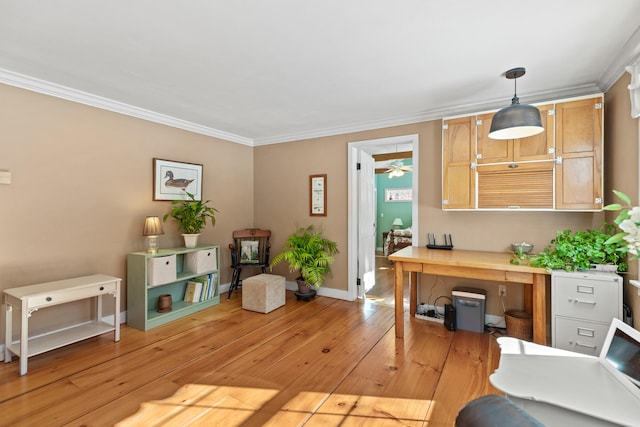 office area with built in desk, light wood finished floors, baseboards, and crown molding