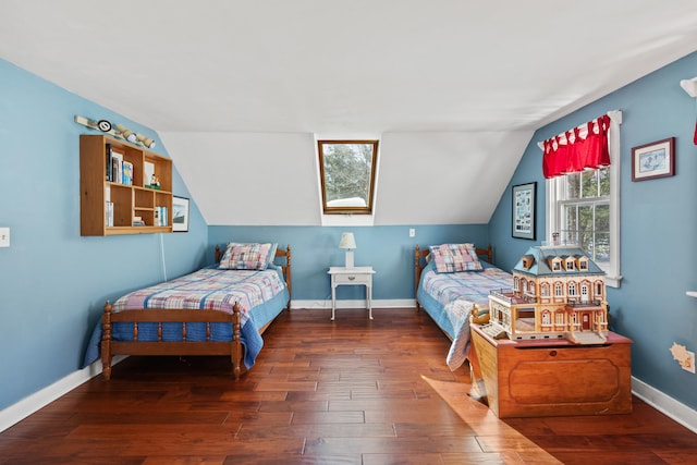 bedroom featuring vaulted ceiling with skylight, hardwood / wood-style floors, and baseboards