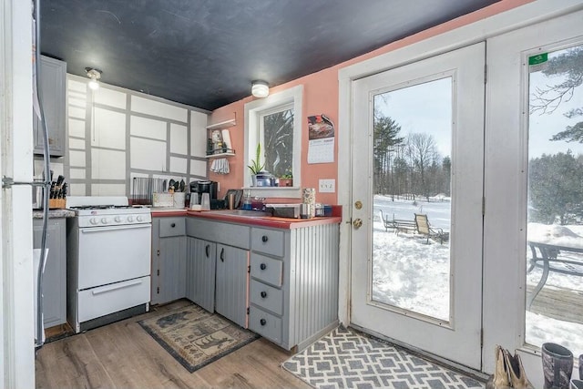 kitchen featuring gray cabinets, sink, gas range gas stove, and light wood-type flooring