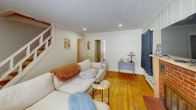 living area with light wood-style floors, crown molding, baseboard heating, and stairs