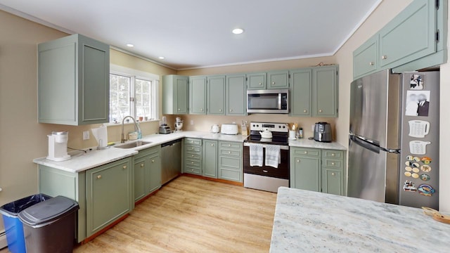 kitchen featuring stainless steel appliances, a sink, light wood finished floors, and green cabinets