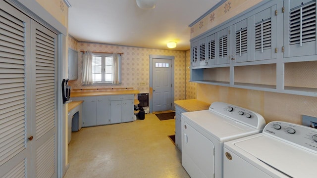 laundry room with washer and clothes dryer, cabinet space, and wallpapered walls