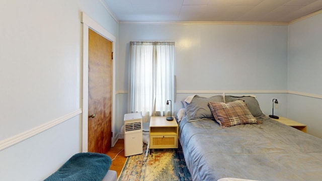 bedroom featuring ornamental molding, multiple windows, and wood finished floors