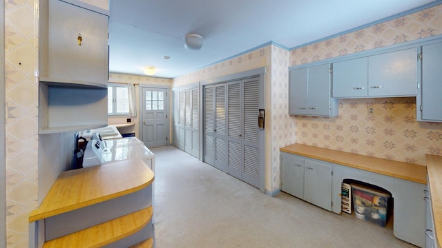 kitchen with wallpapered walls, blue cabinetry, open shelves, and light countertops