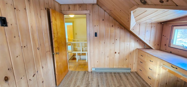 additional living space featuring light wood-type flooring, vaulted ceiling, wood walls, and baseboard heating