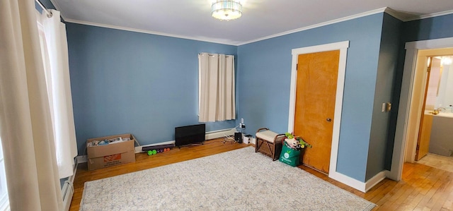 bedroom with ornamental molding, hardwood / wood-style floors, a baseboard radiator, and baseboards