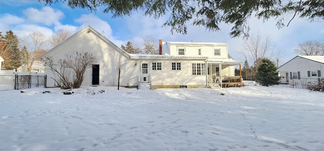 snow covered rear of property featuring a garage and fence